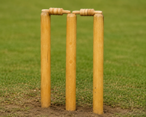 A close-up view of a wooden cricket wicket with stumps and bails set up on a professional pitch.