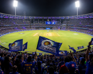A packed cricket stadium illuminated under massive lights with thousands of fans waving flags during an Indian Premier League match.